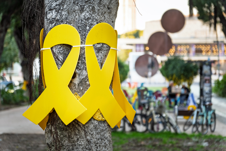 Bring Them Home Now' Installing plastic yellow ribbons tied on tree trunk